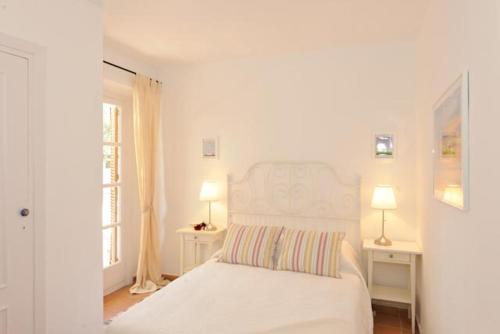 Un dormitorio blanco con una cama blanca y dos lámparas. en Los claveles, en Almuñécar