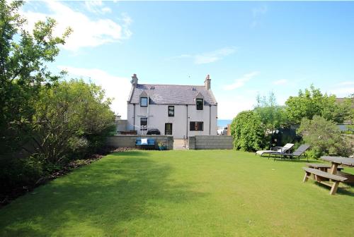 a house with a large yard with a picnic table at Dalwhinnie in Portessie