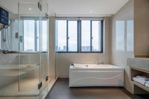 a bathroom with a shower and a tub and a sink at City Comfort Inn Nanning Xingning District Government Maternal and Child Health Hospital in Nanning