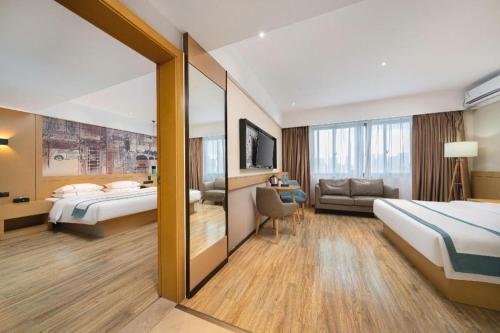 a hotel room with two beds and a couch at City Comfort Inn Nanning Xingning District Government Maternal and Child Health Hospital in Nanning