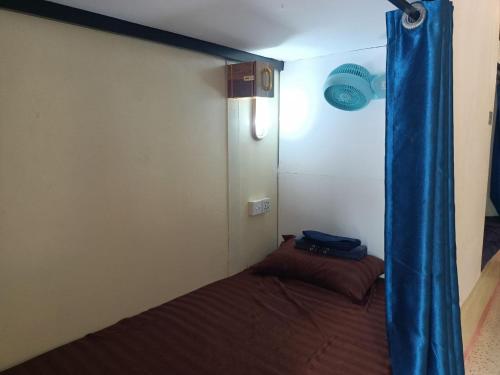 a small room with a bed with a blue curtain at Blue Zone Hostel in Koh Rong