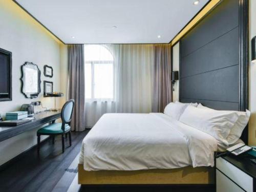 a bedroom with a large bed with a desk and a chair at Xana Hotelle Wuxi Railway Station Zhongshan Road in Wuxi