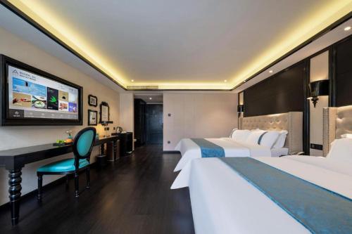 a hotel room with two beds and a desk at Xana Hotelle Wuxi Railway Station Zhongshan Road in Wuxi