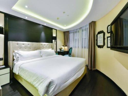 a hotel room with a large bed and a television at Xana Hotelle Wuxi Railway Station Zhongshan Road in Wuxi