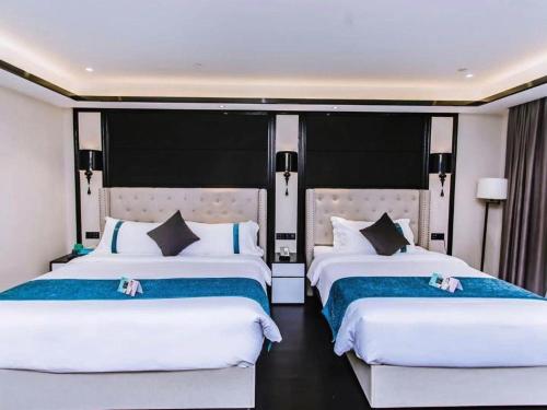 two beds in a hotel room with white sheets at Xana Hotelle Wuxi Railway Station Zhongshan Road in Wuxi
