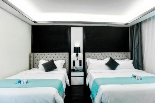 a bedroom with two beds with blue and white sheets at Xana Hotelle Wuxi Railway Station Zhongshan Road in Wuxi