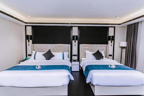 two beds in a hotel room with white sheets at Xana Hotelle Wuxi Railway Station Zhongshan Road in Wuxi
