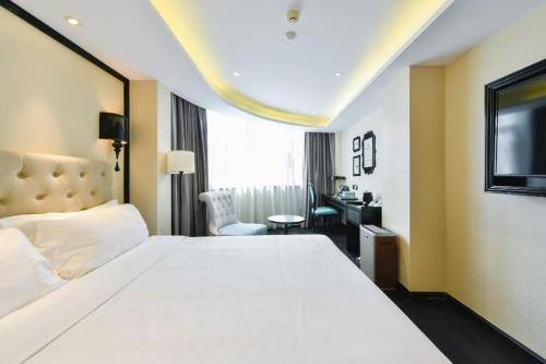 a bedroom with a large white bed and a desk at Xana Hotelle Wuxi Railway Station Zhongshan Road in Wuxi