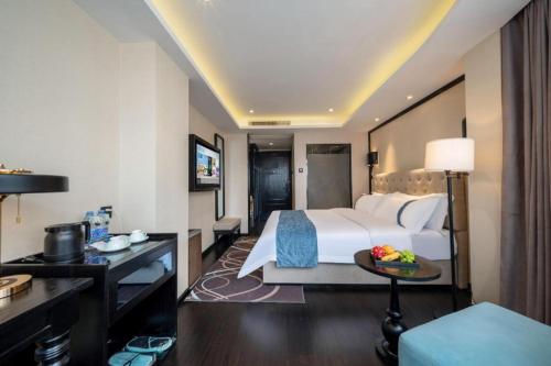 a hotel room with a large bed and a table at Xana Hotelle Wuxi Railway Station Zhongshan Road in Wuxi