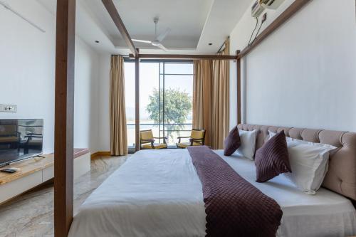 a bedroom with a large bed and a large window at Heartland- Ganga Villa with Jacuzzi and private lift in Rishīkesh