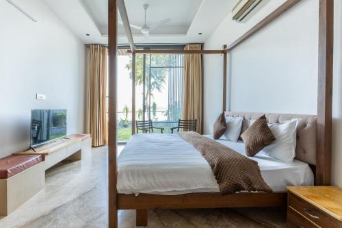 a bedroom with a canopy bed and a television at Heartland- Ganga Villa with Jacuzzi and private lift in Rishīkesh