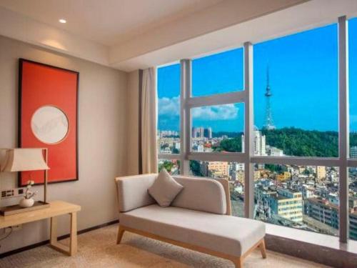 a living room with a couch and a large window at E-Cheng Hotel Yangjiang Baili Plaza in Yangjiang