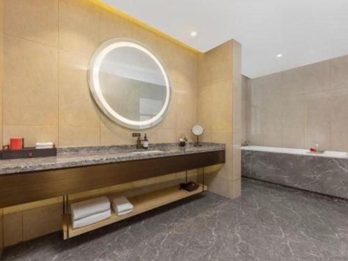 a bathroom with a sink and a mirror and a tub at E-Cheng Hotel Yangjiang Baili Plaza in Yangjiang