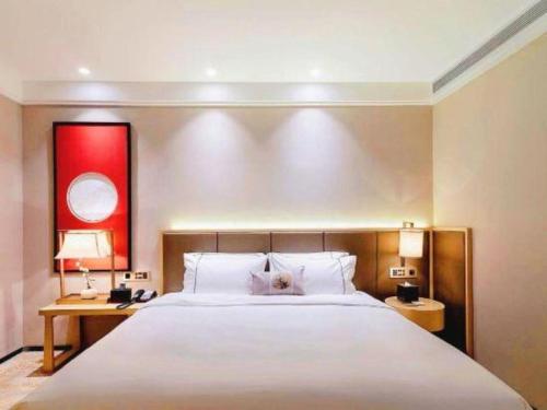 a bedroom with a large white bed and a desk at E-Cheng Hotel Yangjiang Baili Plaza in Yangjiang