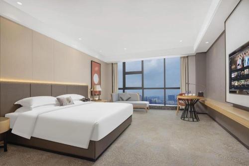 a bedroom with a large white bed and a television at E-Cheng Hotel Yangjiang Baili Plaza in Yangjiang
