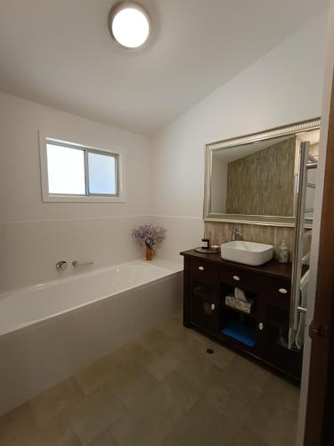 a bathroom with a tub and a sink and a mirror at Barossa Views Homestay in Barossa