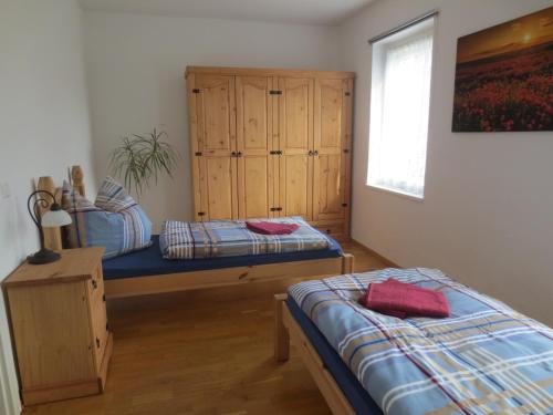 1 dormitorio con 2 camas y armario de madera en Ferienwohnung Creutzer, en Gottscheina