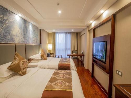 a hotel room with two beds and a flat screen tv at GreenTree Eastern Hotel Linyi Linshu County Aegean Sea in Linyi