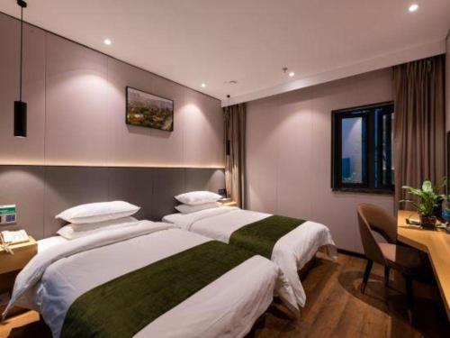 a hotel room with two beds and a desk and a desk at Green Tree Inn Express Fuzhou Three Lanes and Seven Alleys Nanmendou Metro Station in Fuzhou