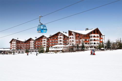 people on a ski lift in front of a ski resort at Kempinski Hotel Grand Arena Bansko in Bansko