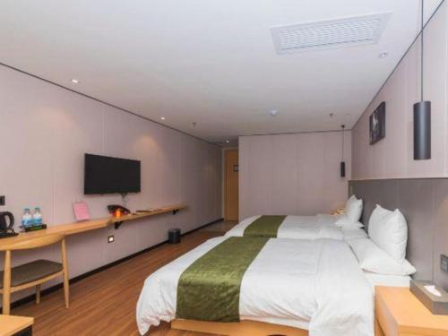 a bedroom with a bed and a desk and a tv at Green Tree Inn Express Fuzhou Three Lanes and Seven Alleys Nanmendou Metro Station in Fuzhou