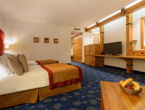 a hotel room with a bed and a flat screen tv at Kempinski Hotel Grand Arena Bansko in Bansko