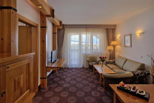 a hotel room with a couch and a television at Kempinski Hotel Grand Arena Bansko in Bansko