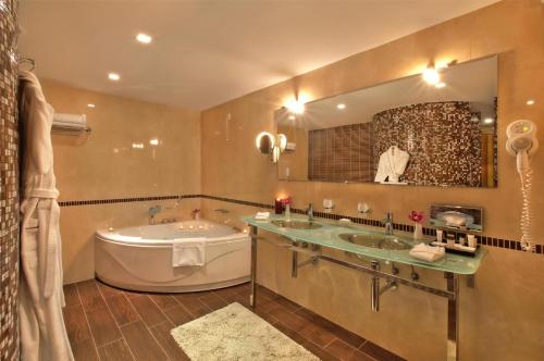 a bathroom with two sinks and a tub and a large mirror at Kempinski Hotel Grand Arena Bansko in Bansko
