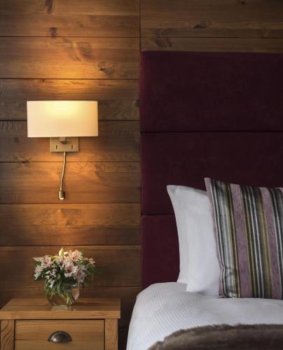 a bedroom with a bed with a lamp and flowers on a table at Kempinski Hotel Grand Arena Bansko in Bansko