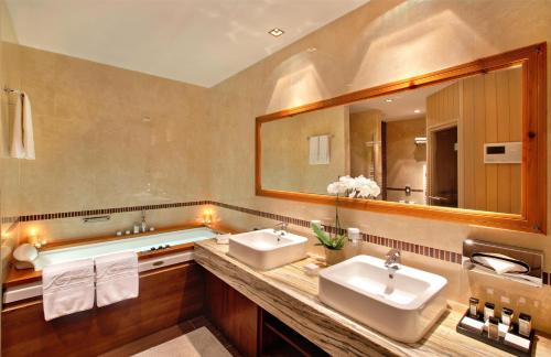 a bathroom with two sinks and a large mirror at Kempinski Hotel Grand Arena Bansko in Bansko