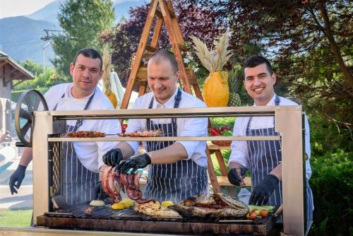 a group of three men cooking food on a grill at Kempinski Hotel Grand Arena Bansko in Bansko