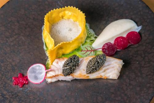 a plate of food with a piece of fish and vegetables at Kempinski Hotel Grand Arena Bansko in Bansko
