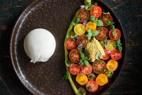 a plate of food with tomatoes and a white spoon at Kempinski Hotel Grand Arena Bansko in Bansko
