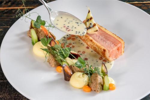 a plate of food with meat and vegetables and a spoon at Kempinski Hotel Grand Arena Bansko in Bansko