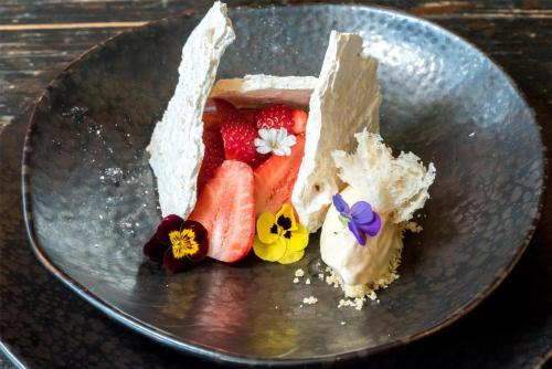 a piece of cake with fruit and flowers on a plate at Kempinski Hotel Grand Arena Bansko in Bansko