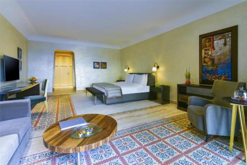 a hotel room with a bed and a living room at Kempinski Hotel Ishtar Dead Sea in Sowayma