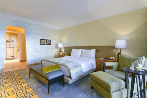 a hotel room with a bed and a chair at Kempinski Hotel Ishtar Dead Sea in Sowayma