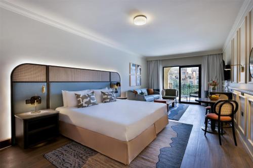 a bedroom with a large bed and a living room at Kempinski Hotel San Lawrenz in San Lawrenz