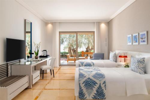 a hotel room with two beds and a television at Kempinski Hotel Ishtar Dead Sea in Sowayma