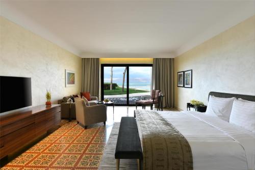 a hotel room with a bed and a flat screen tv at Kempinski Hotel Ishtar Dead Sea in Sowayma