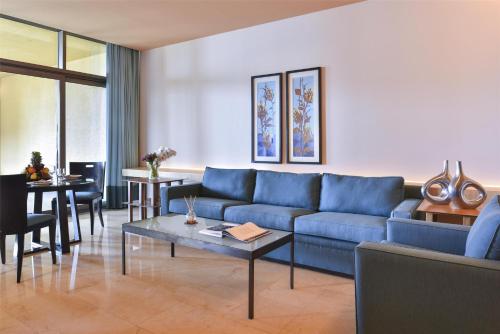 a living room with a blue couch and a table at Kempinski Hotel Ishtar Dead Sea in Sowayma