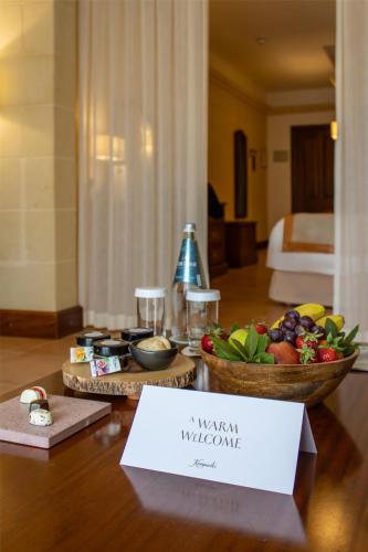 a table with a bowl of fruit and a plate of food at Kempinski Hotel San Lawrenz in San Lawrenz