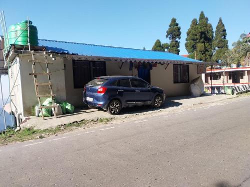 a blue car parked in front of a house at Dumfu Homestay in Darjeeling