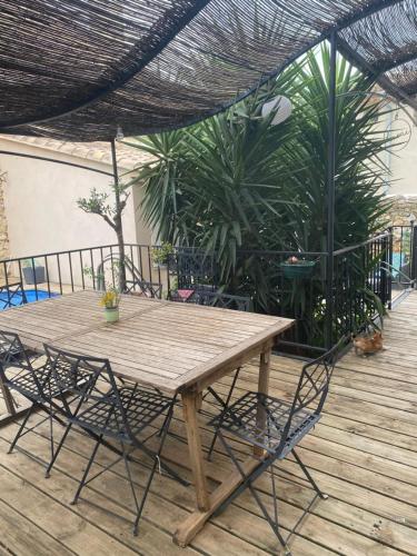 une table et des chaises en bois sur une terrasse dans l'établissement Villa, à Eyguières