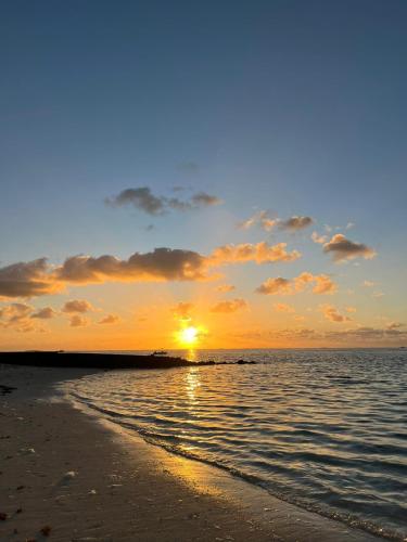 a sunset on the beach with the sun setting at Kot Nou - Kwizine Mama Manze Lakaz in Mahébourg