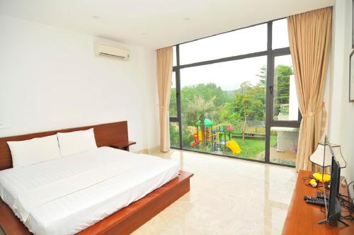 une chambre avec un lit et une vue sur une aire de jeux dans l'établissement Villa T100 - 5 phòng ngủ Chủ Tự Doanh tại FLAMIGO ĐẠI LẢI RESORT, à Phúc Yên