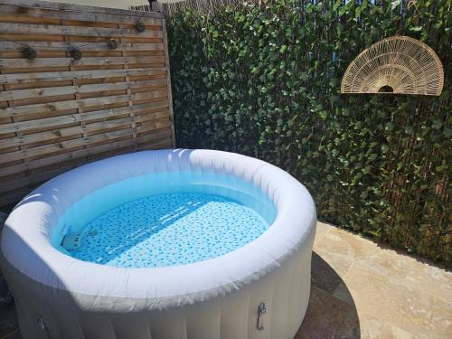 a hot tub in a backyard with a hedge at Havre de paix climatisé vers Gordes - Spa & nature in Beaumettes