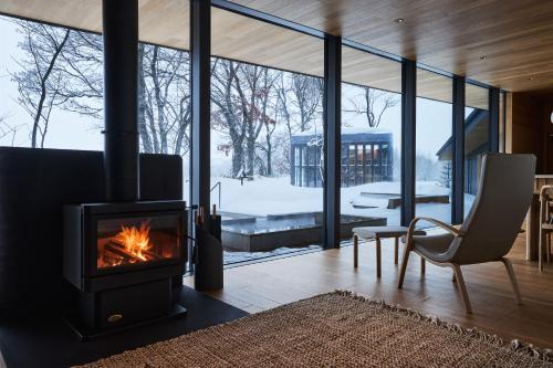 a living room with a fireplace and a chair at SONEKA in Kitahiroshima