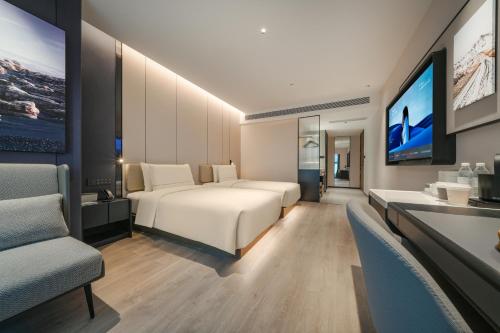 重慶市にあるAtour Hotel Chongqing West Railway Station Xinqiao Hospitalのベッド2台とテレビがあるホテルの部屋