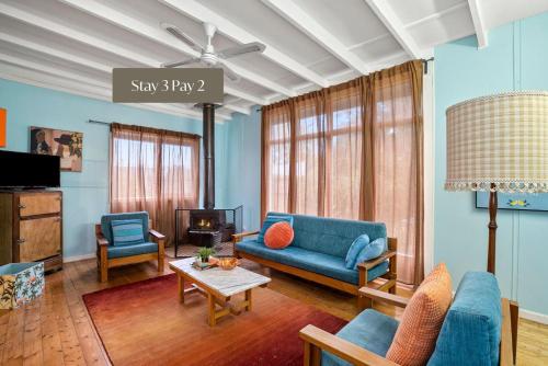 a living room with a blue couch and chairs at Retro Beach Babe 100 metres to the beach in Tootgarook